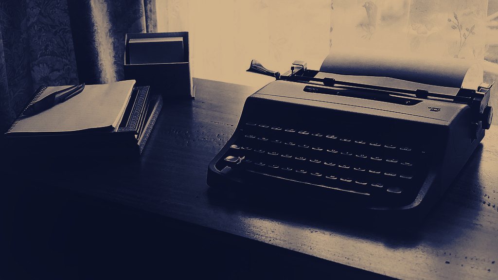 A typewriter on a desk, graded in navy and brass