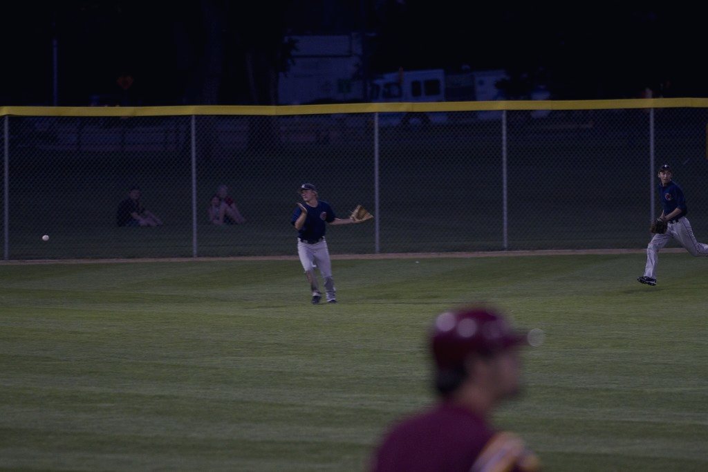 An outfielder under grey night clouds, watching a fly ball
